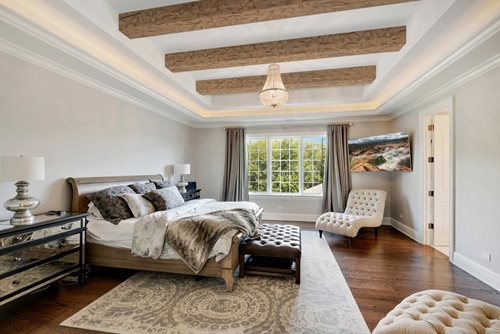Luxury bedroom with thick ceiling beams and a chandelier